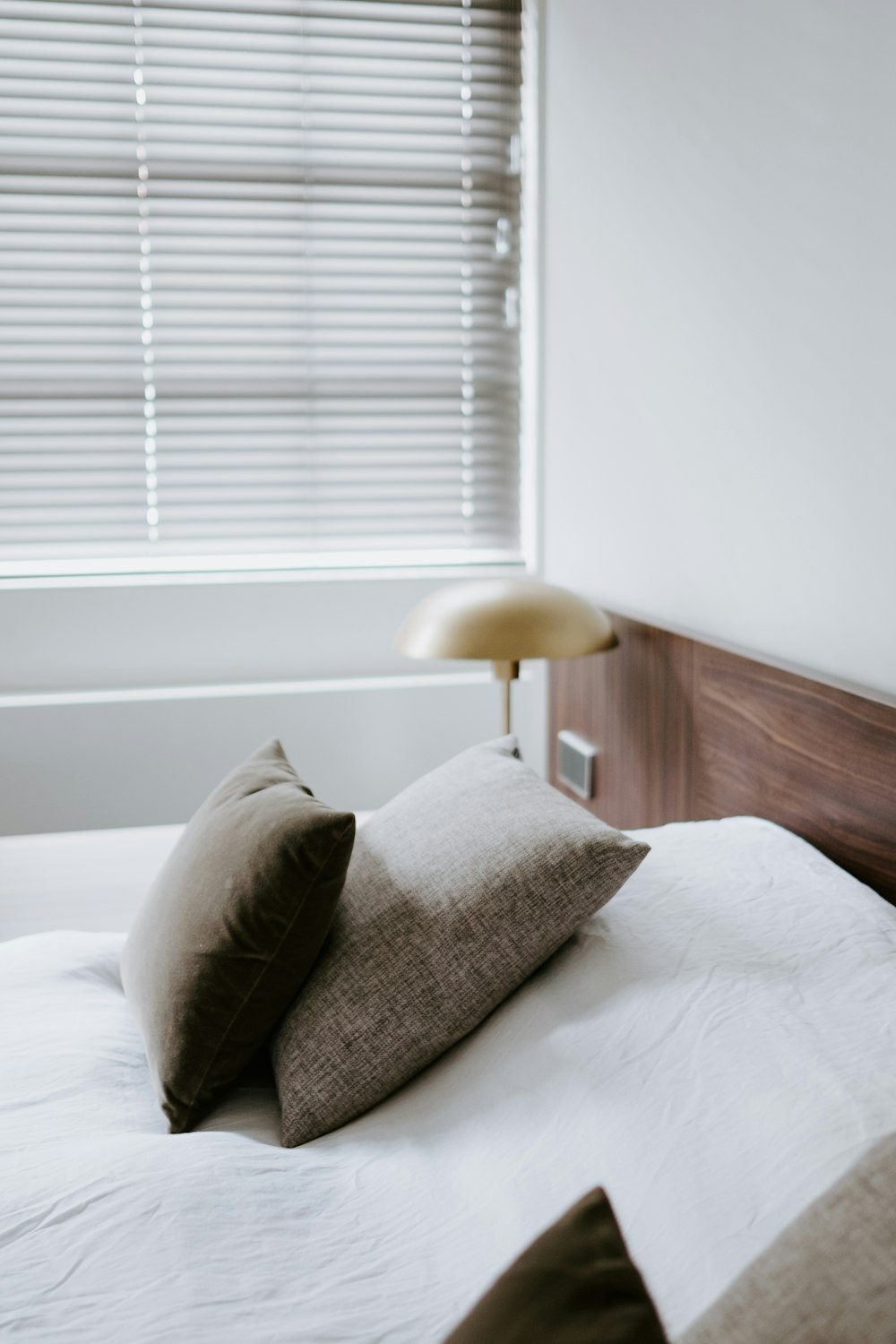 bed with pillows near Venetian blinds