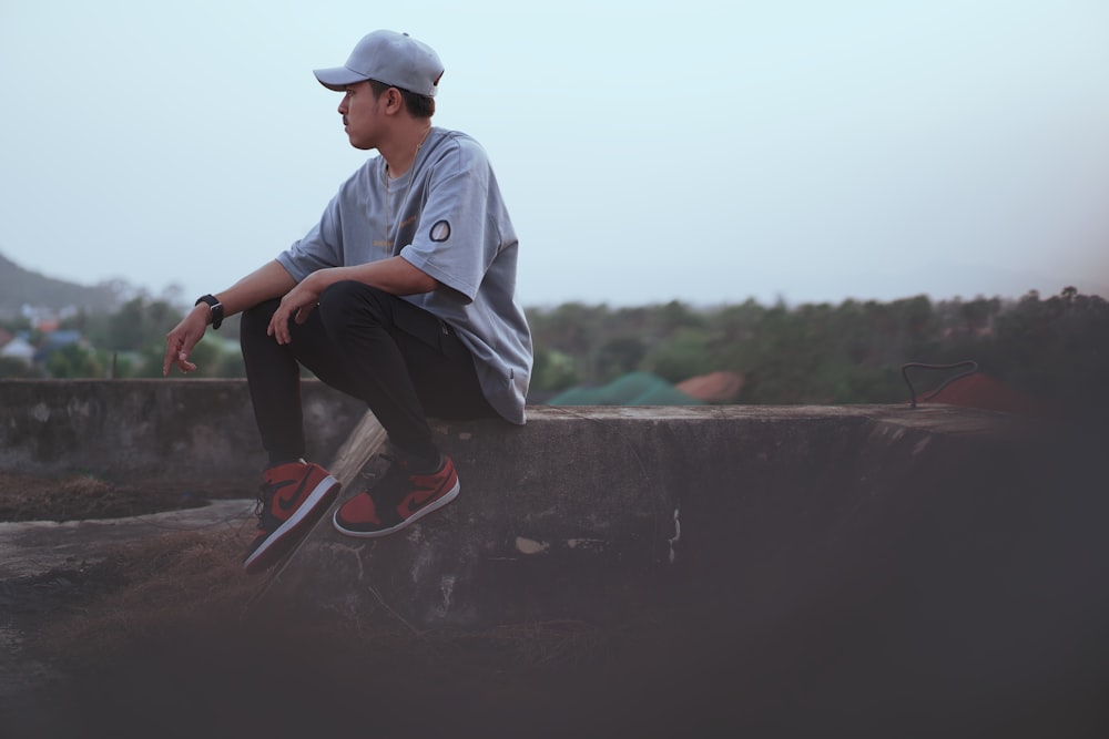 selective focus photo of man sitting on concrete slab