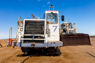 A powerful bulldozer clearing a rugged Texas landscape under a bright blue sky.