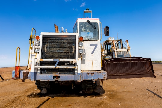 A bulldozer clearing sandy terrain under a bright blue sky in Riyadh.