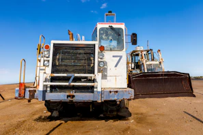 Close-up of a bulldozer blade pushing earth with dust rising in a sunny environment