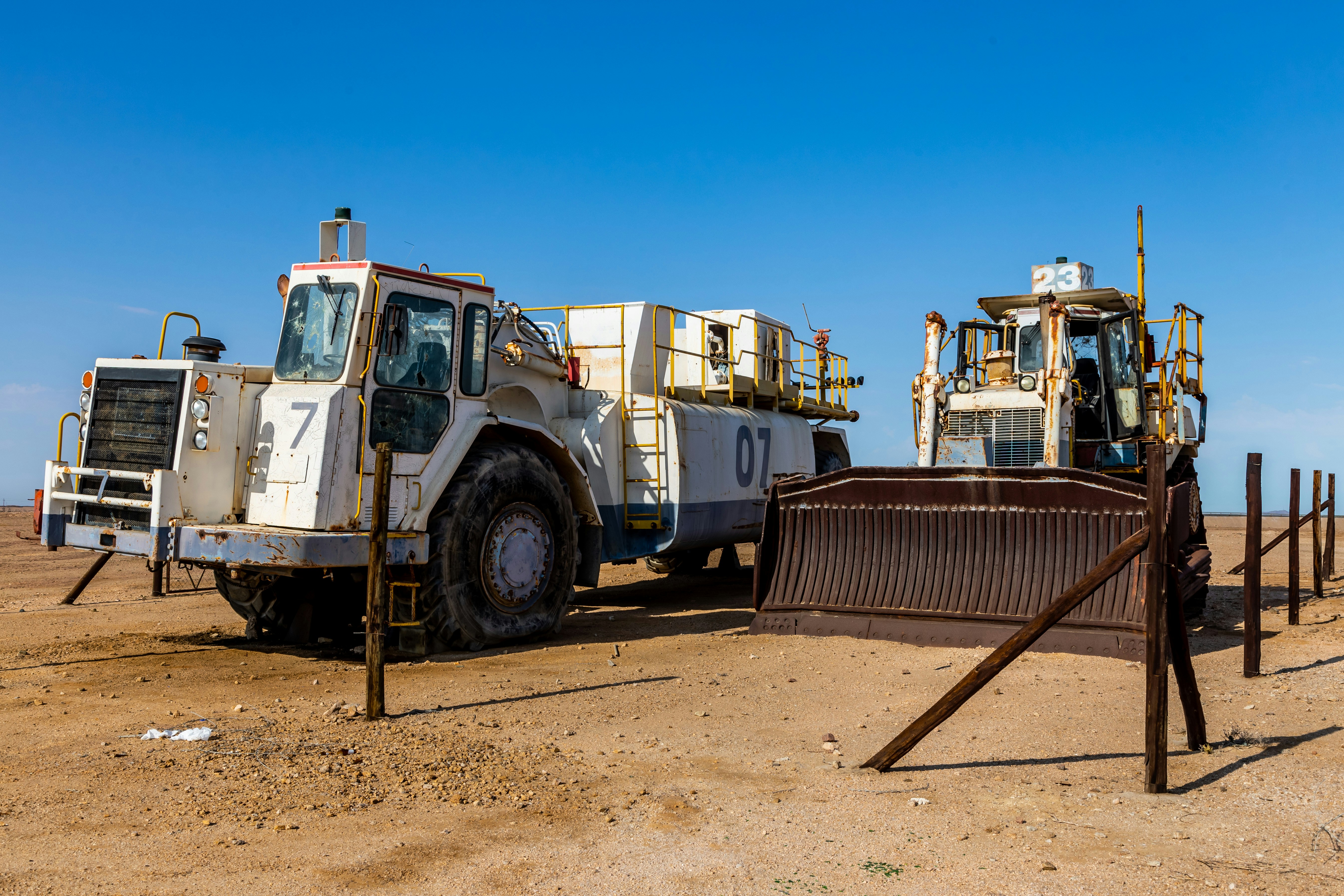 a couple of trucks parked next to each other on a dirt field