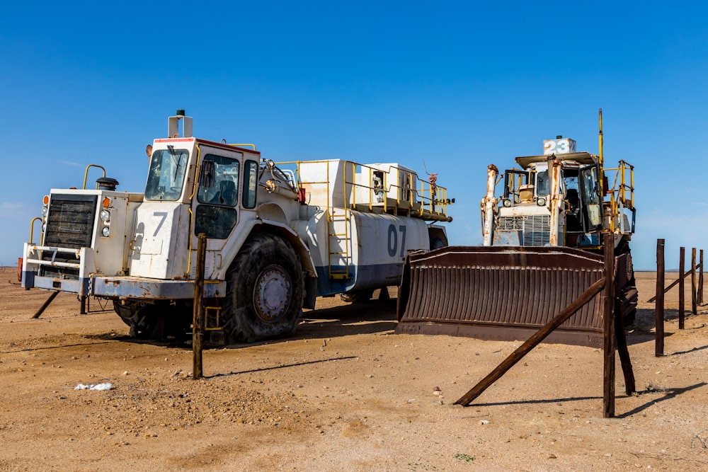 um par de caminhões estacionados um ao lado do outro em um campo de terra