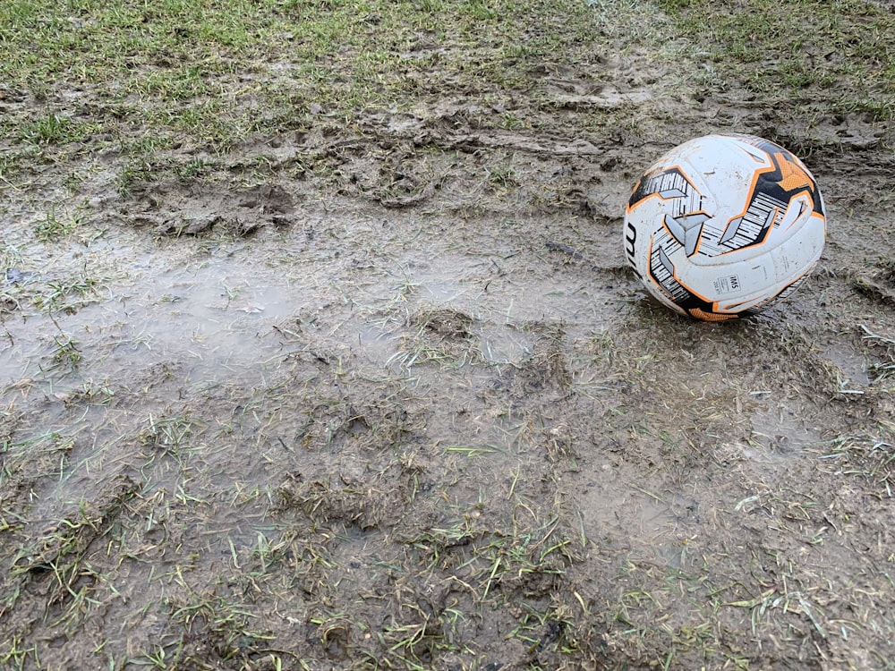 white and orange soccer ball on the ground