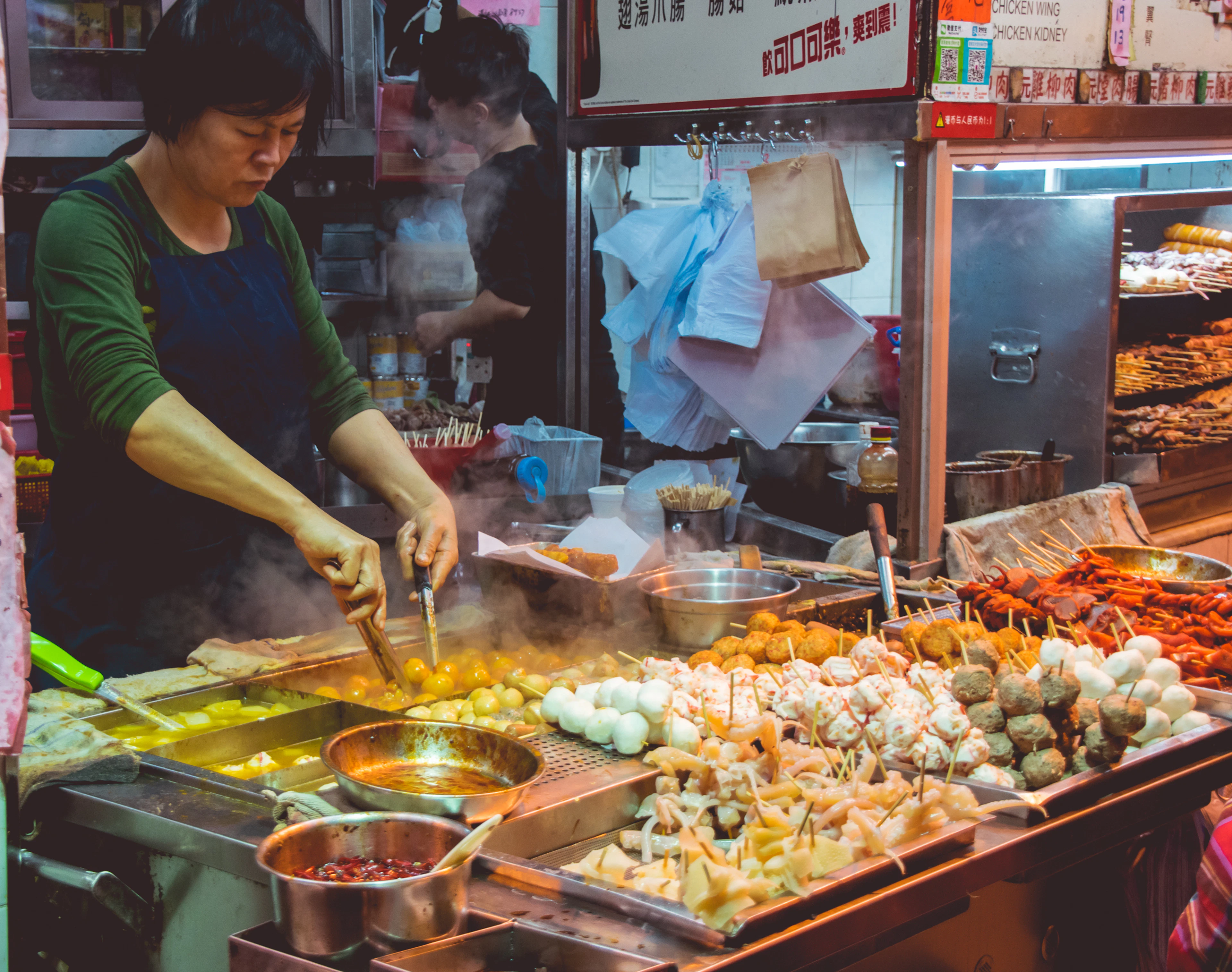 A cook working a brightly lit street food stall at night