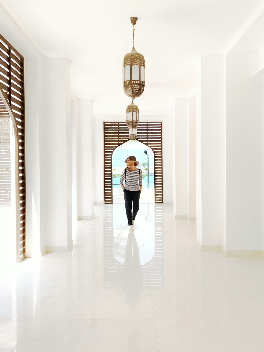 person wearing black pants standing below gold pendant lamp