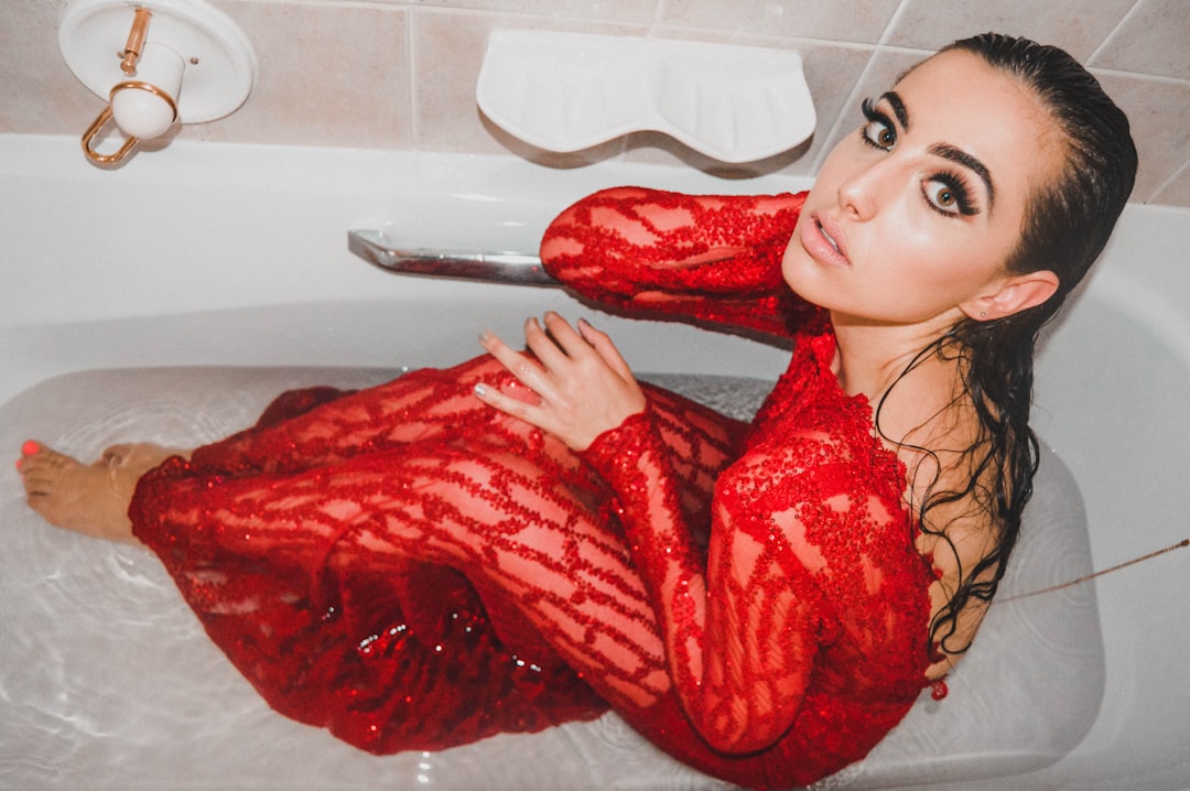 woman in red lace long-sleeved dress sitting on bathtub