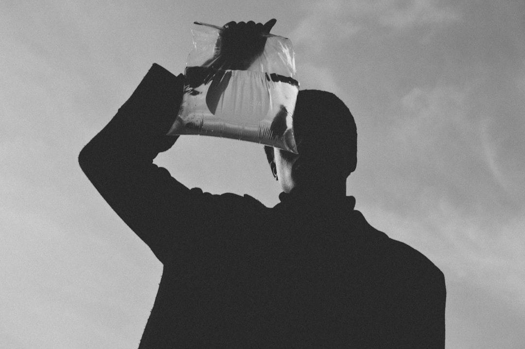 grayscale photo of person holding plastic with water and fish