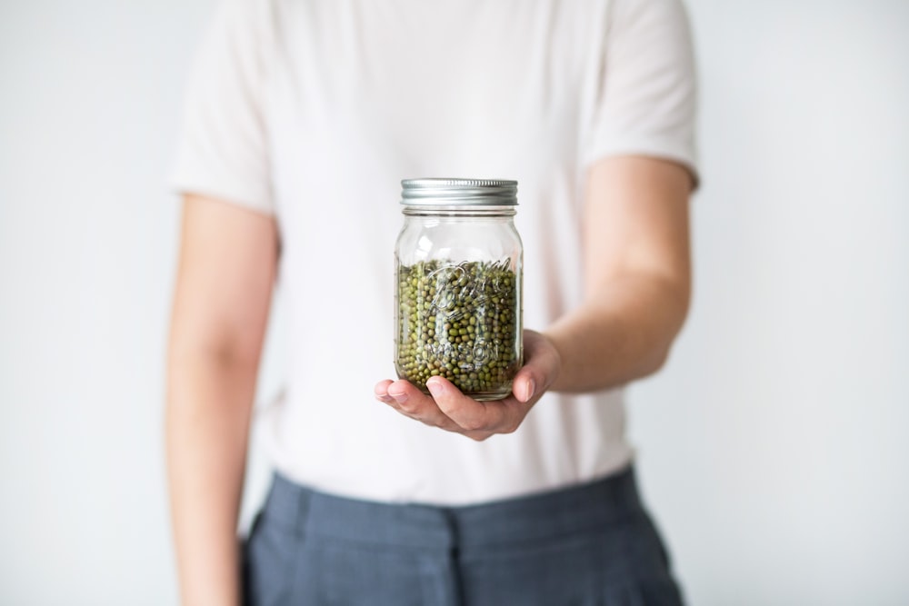 person holding clear glass jar