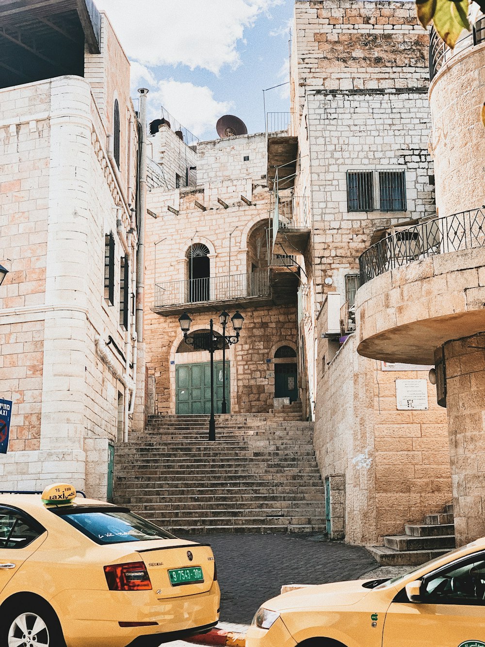 two yellow vehicles near buildings at daytime