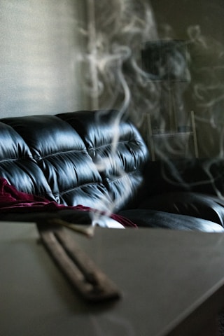 Cozy living room with lit incense and soft natural light creating a peaceful atmosphere.