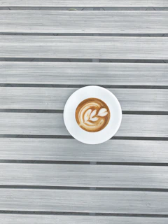 Barista preparing a cappuccino with latte art in a minimalist setting.