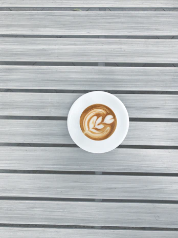 Barista preparing a cappuccino with latte art in a minimalist setting.