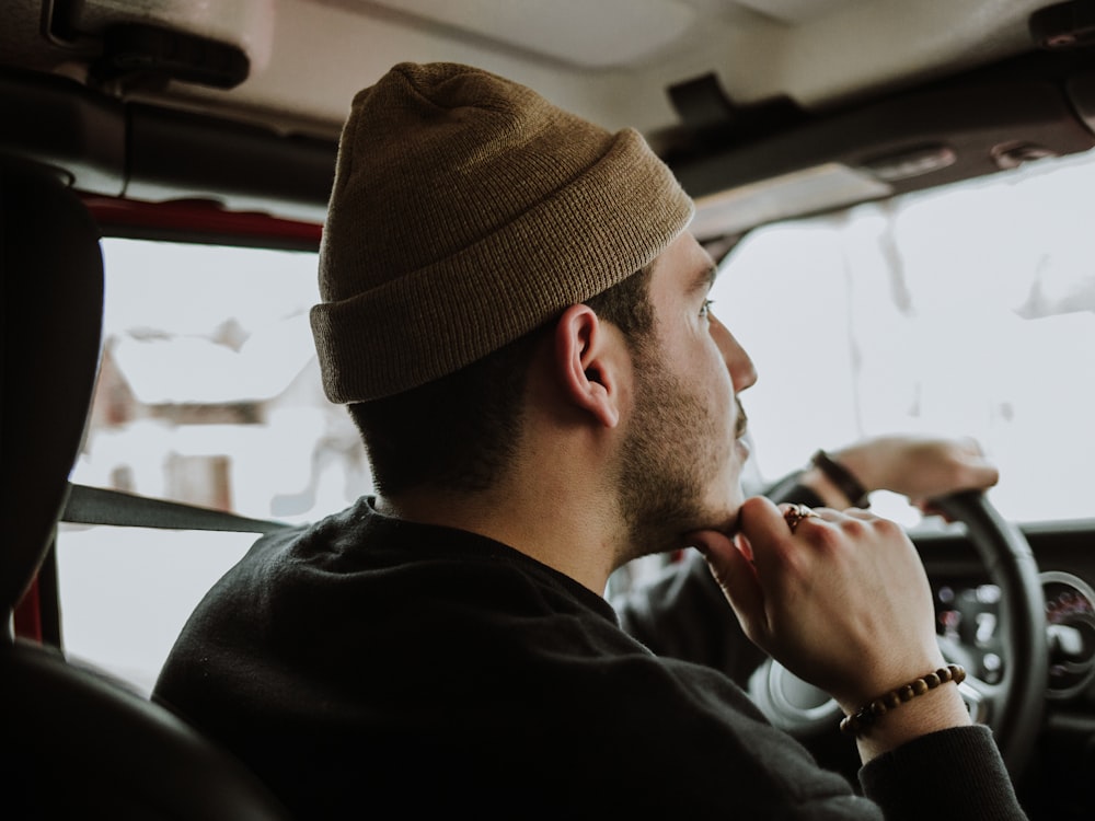 man driving while touching his chin