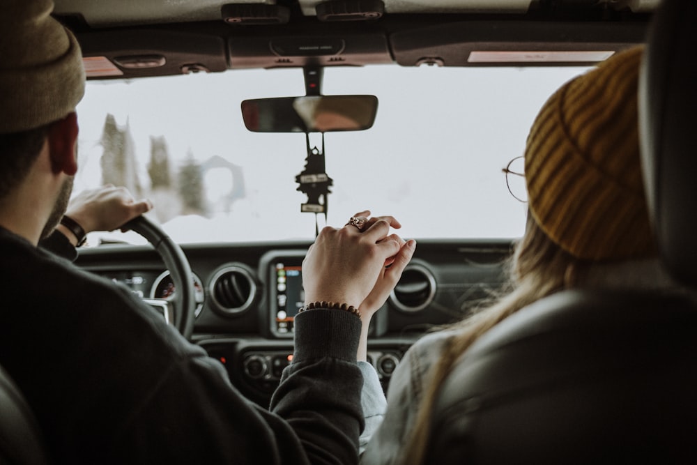 man driving car while holding woman's hand