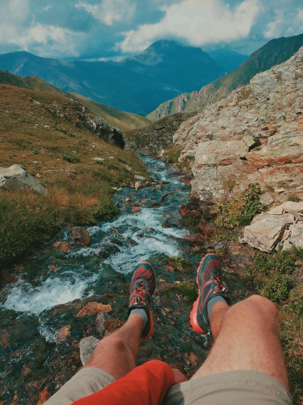 person sitting near stream and rocks