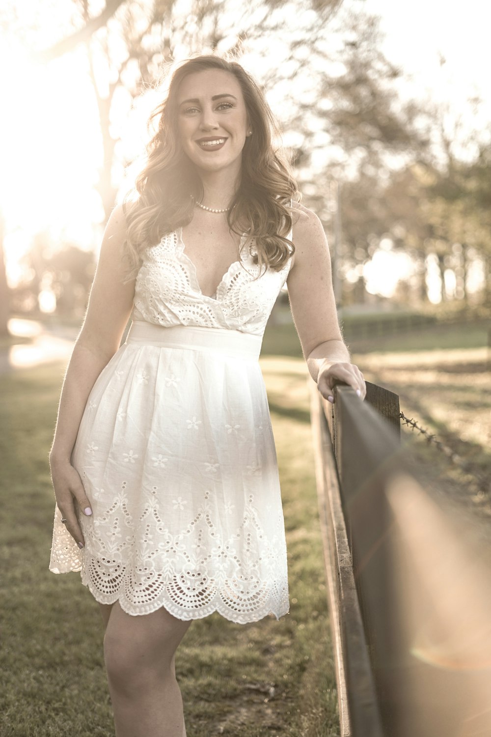 selective focus photo of woman in white dress near fence