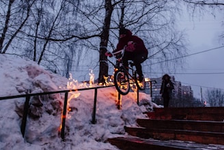 man doing bicycle tricks on hand rail during winter