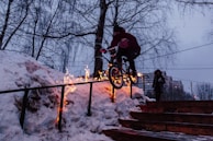 man doing bicycle tricks on hand rail during winter