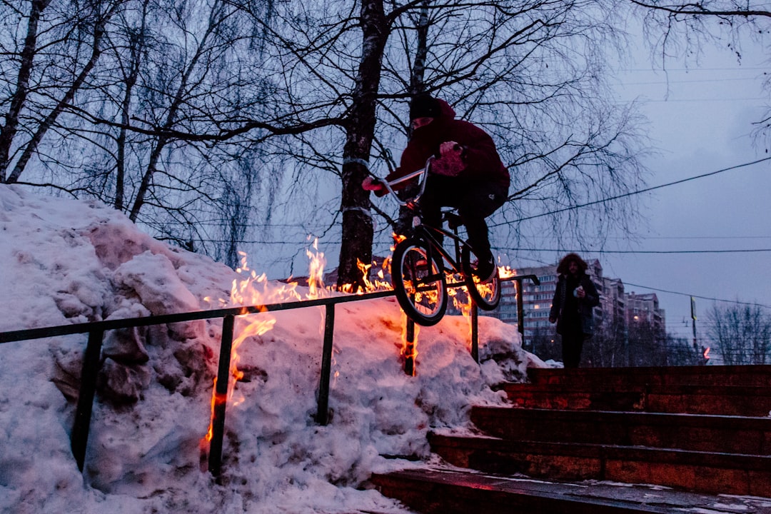 man doing bicycle tricks on hand rail during winter