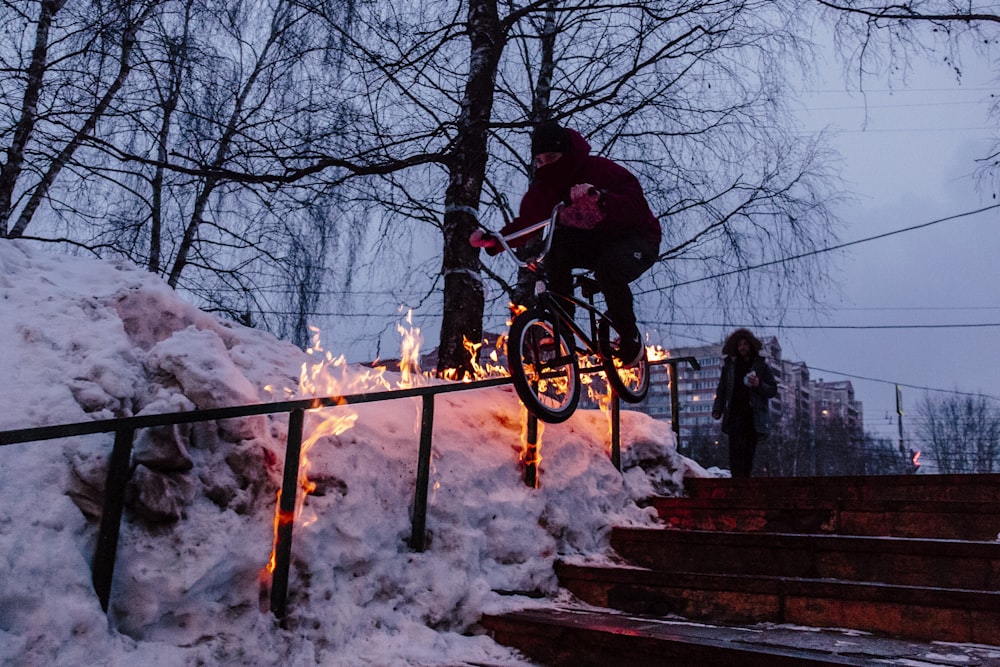 man doing bicycle tricks on hand rail during winter