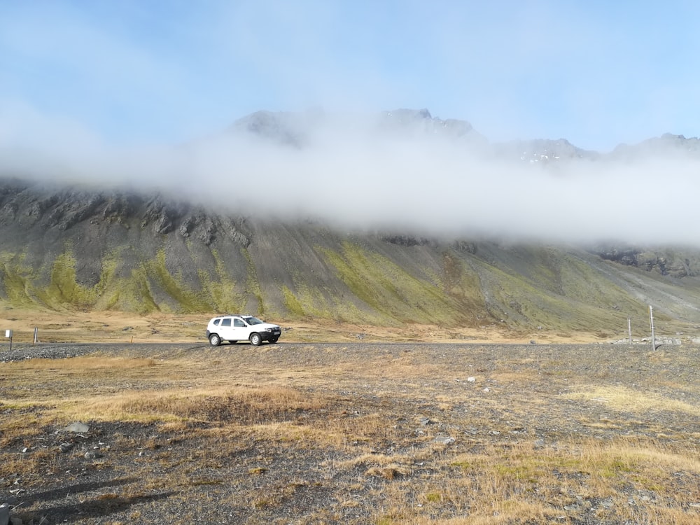 white SUV running on soil over clouds