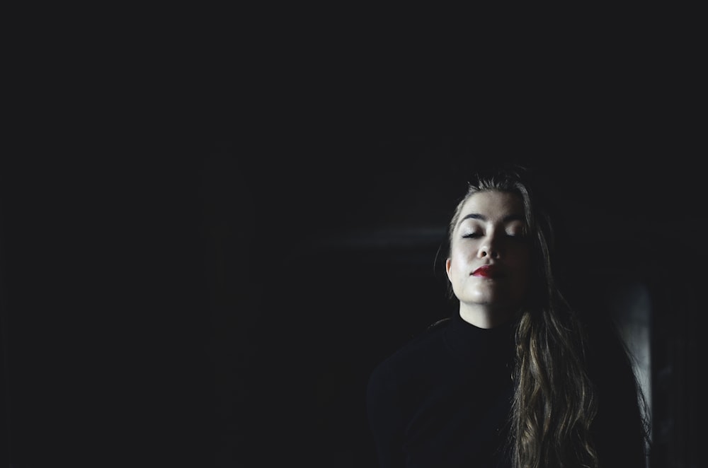 woman wearing black crew-neck top inside black room