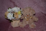 Close-up of a soft teddy bear holding a small bouquet of flowers