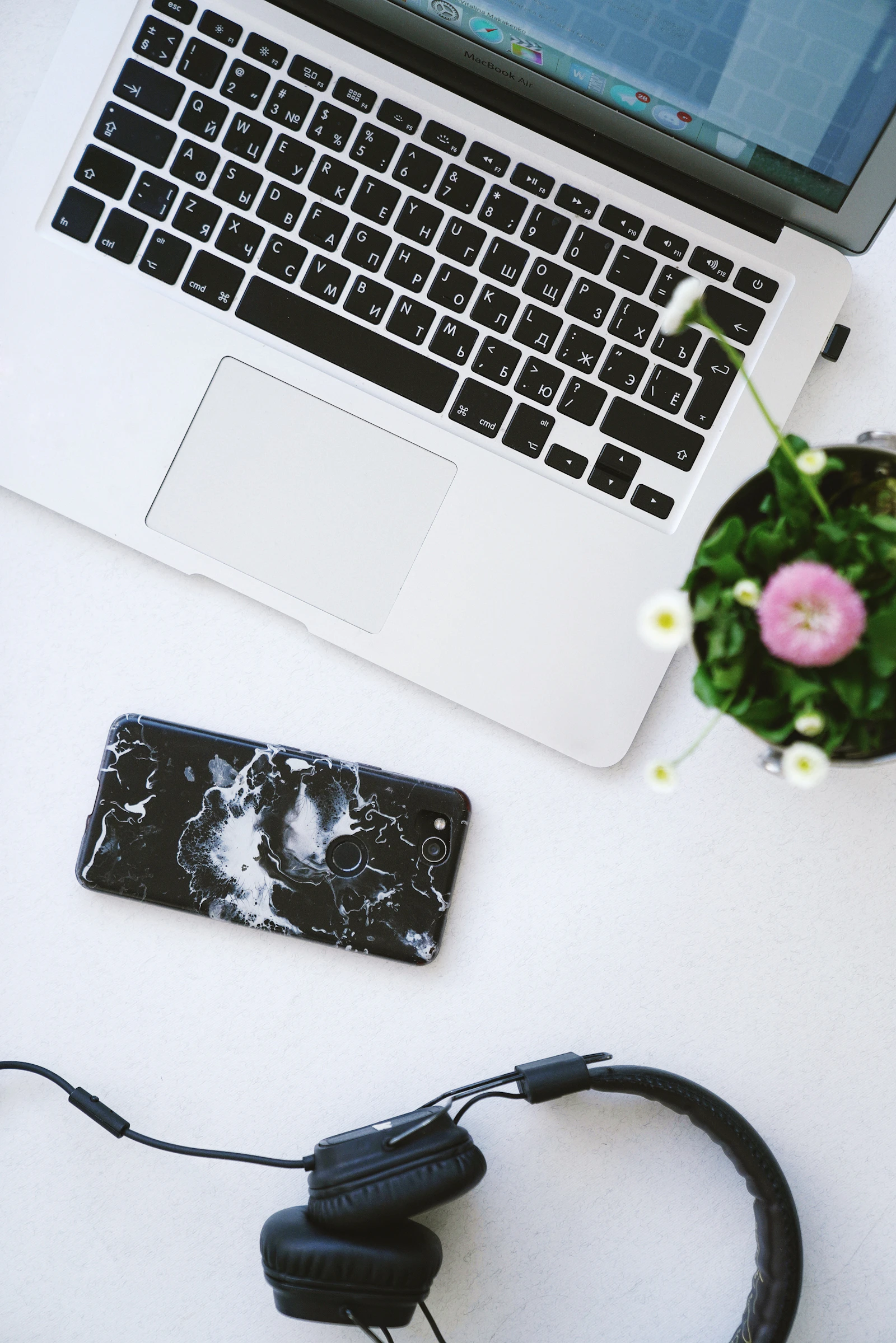 Auriculares negros, teléfono inteligente y MacBook sobre un escritorio minimalista oscuro