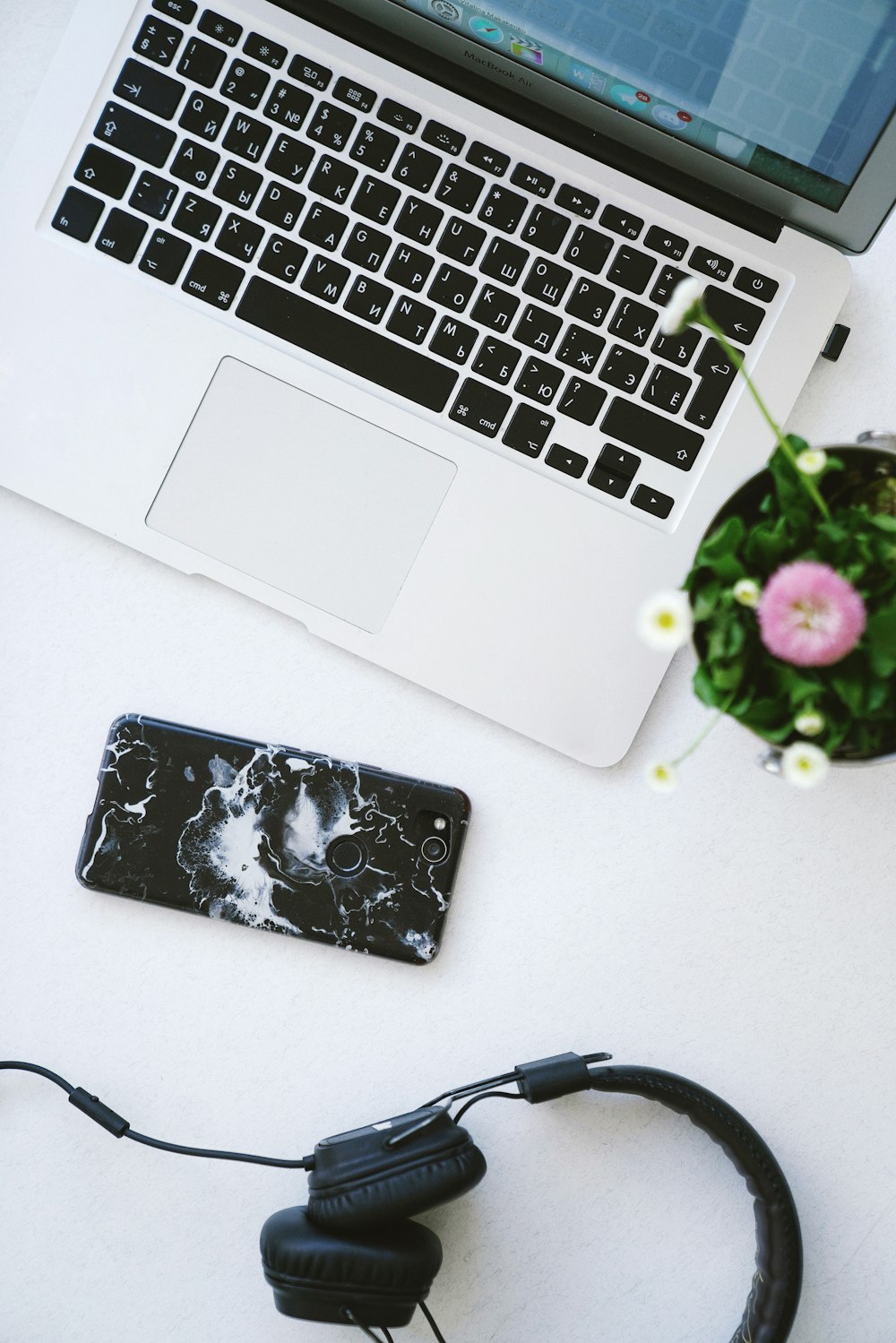 black headphones, smartphone and MacBook on table