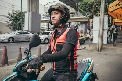 A comfortable motorcycle taxi rider wearing a helmet, ready to pick up a passenger in an urban setting.