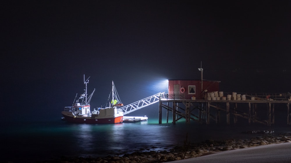 white and red trawler dock at nighttime