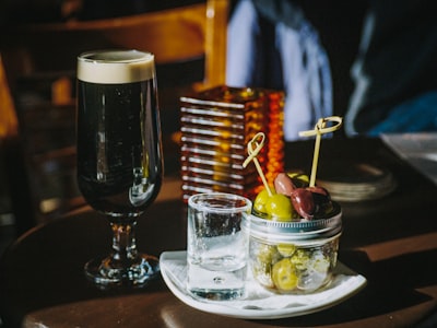 clear shot glass beside liquid filled footed glass st. paddy's day google meet background