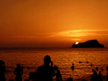 Sunset view over the Red Sea with silhouettes of snorkelers and distant islands.
