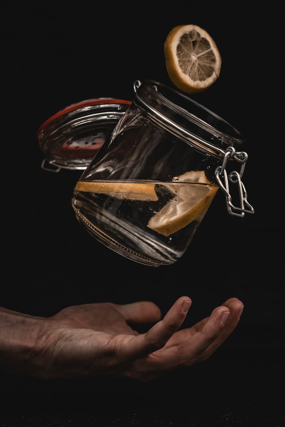clear glass jar with water and sliced lemon over person's hand