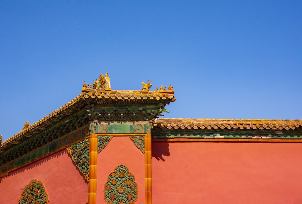 a red building with a golden roof and a blue sky