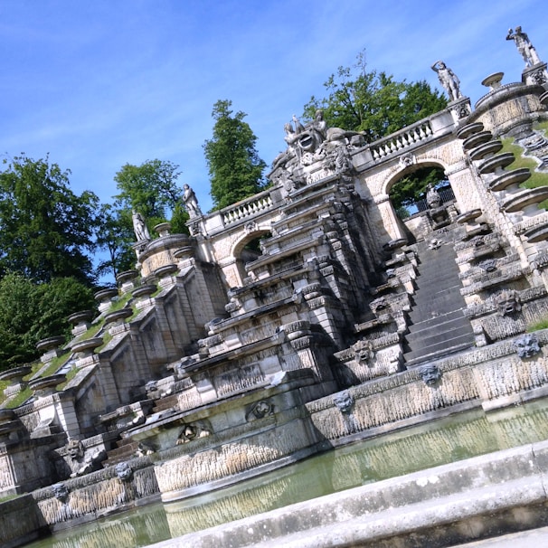 An intricately designed marble fountain surrounded by lush greenery.