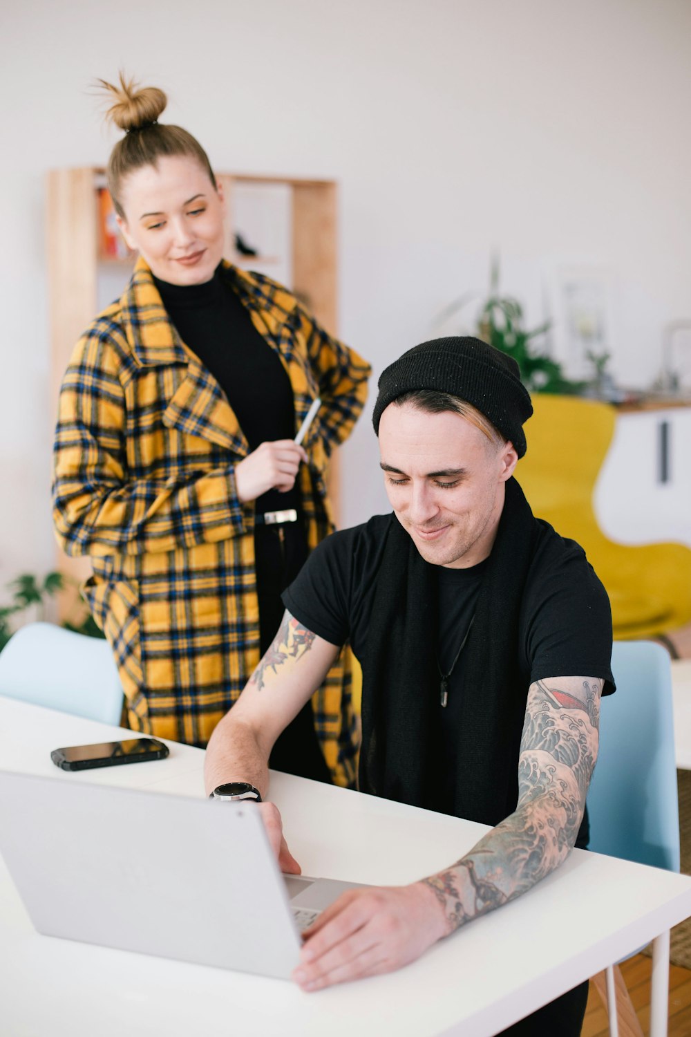 man using laptop beside woman holding pen