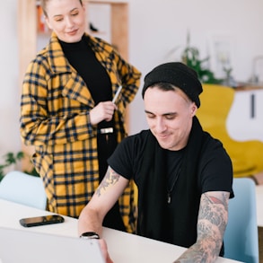 man using laptop beside woman holding pen