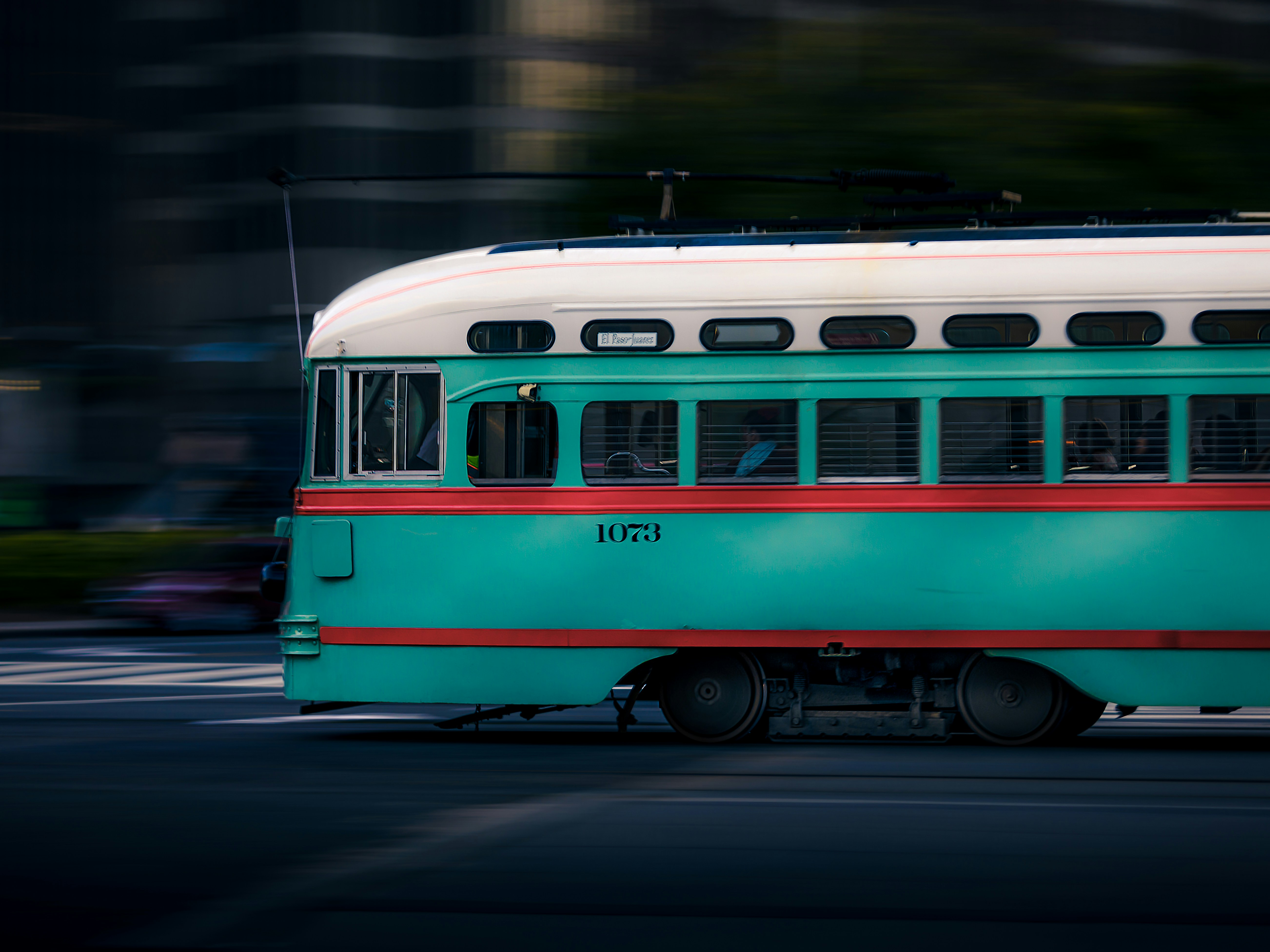 teal and white train running on road