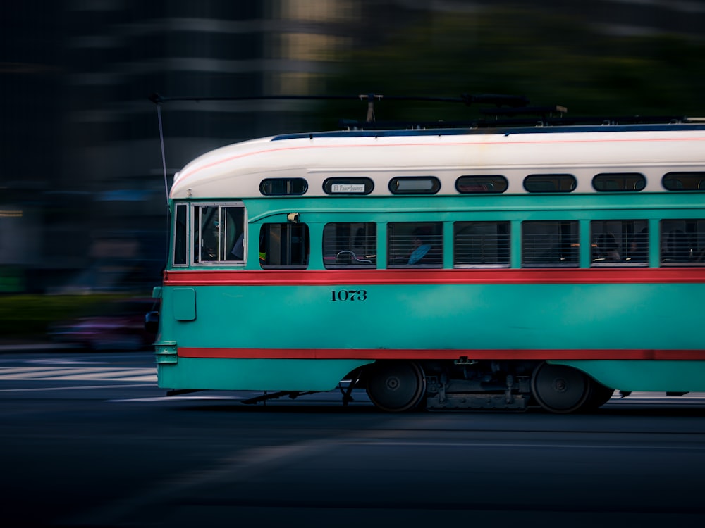 teal and white train running on road