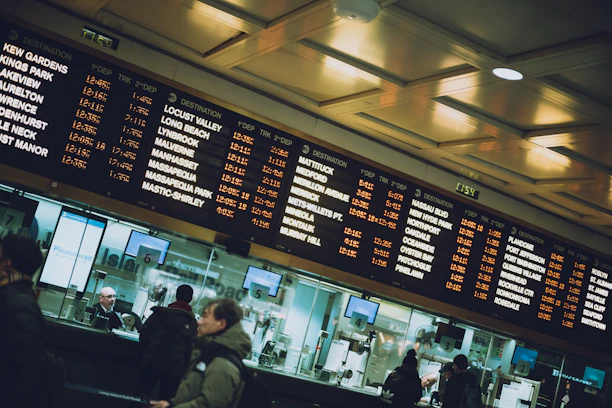 A friendly travel expert assisting a customer over the phone with train schedules in the background.