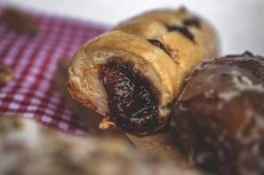 Close-up of a golden, flaky pastizzi resting on a rustic wooden board with a backdrop of warm, earthy tones.