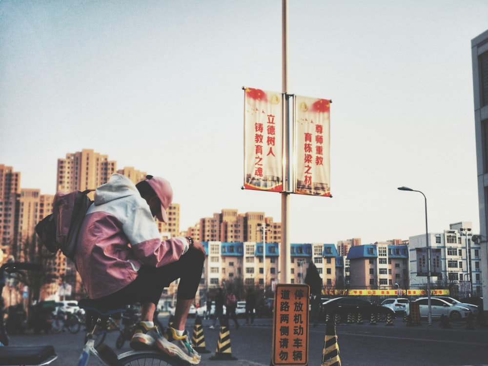 man sitting on bicycle near kanji script signage