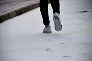 A person applying salt on an icy sidewalk.