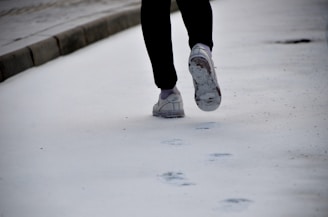 A person applying salt on an icy sidewalk.