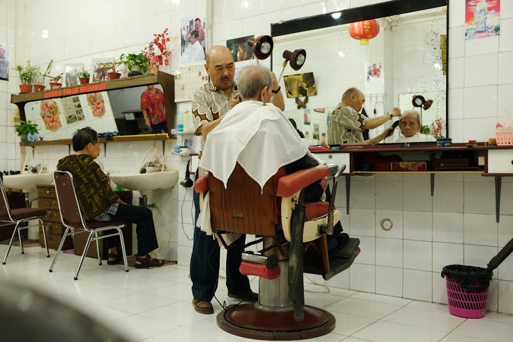 woman cutting the hair of man sitting on barber armchair