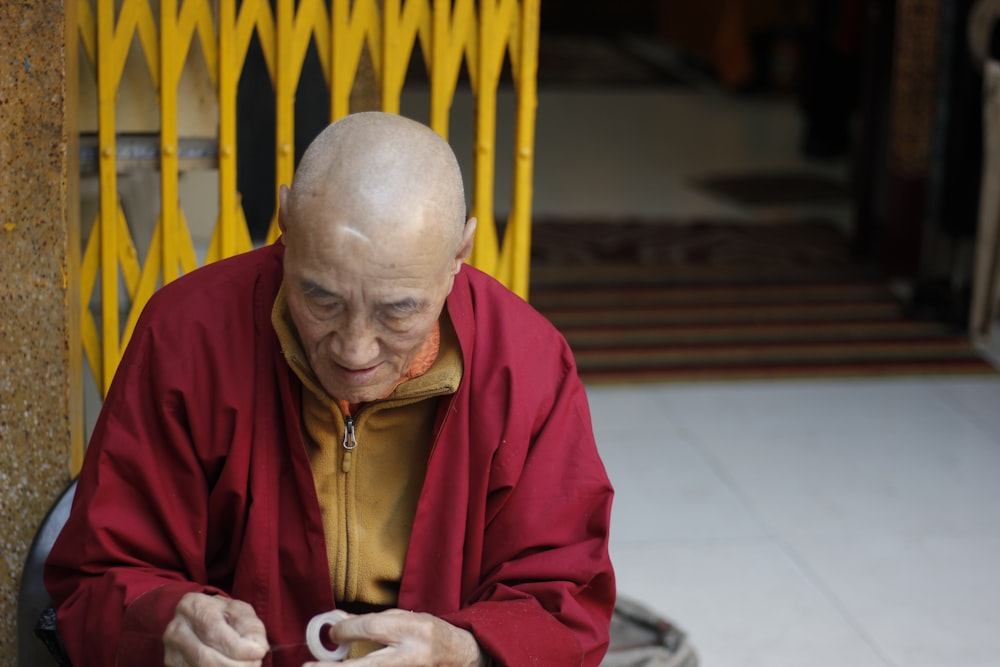 man in red jacket sitting in front of scissors gate