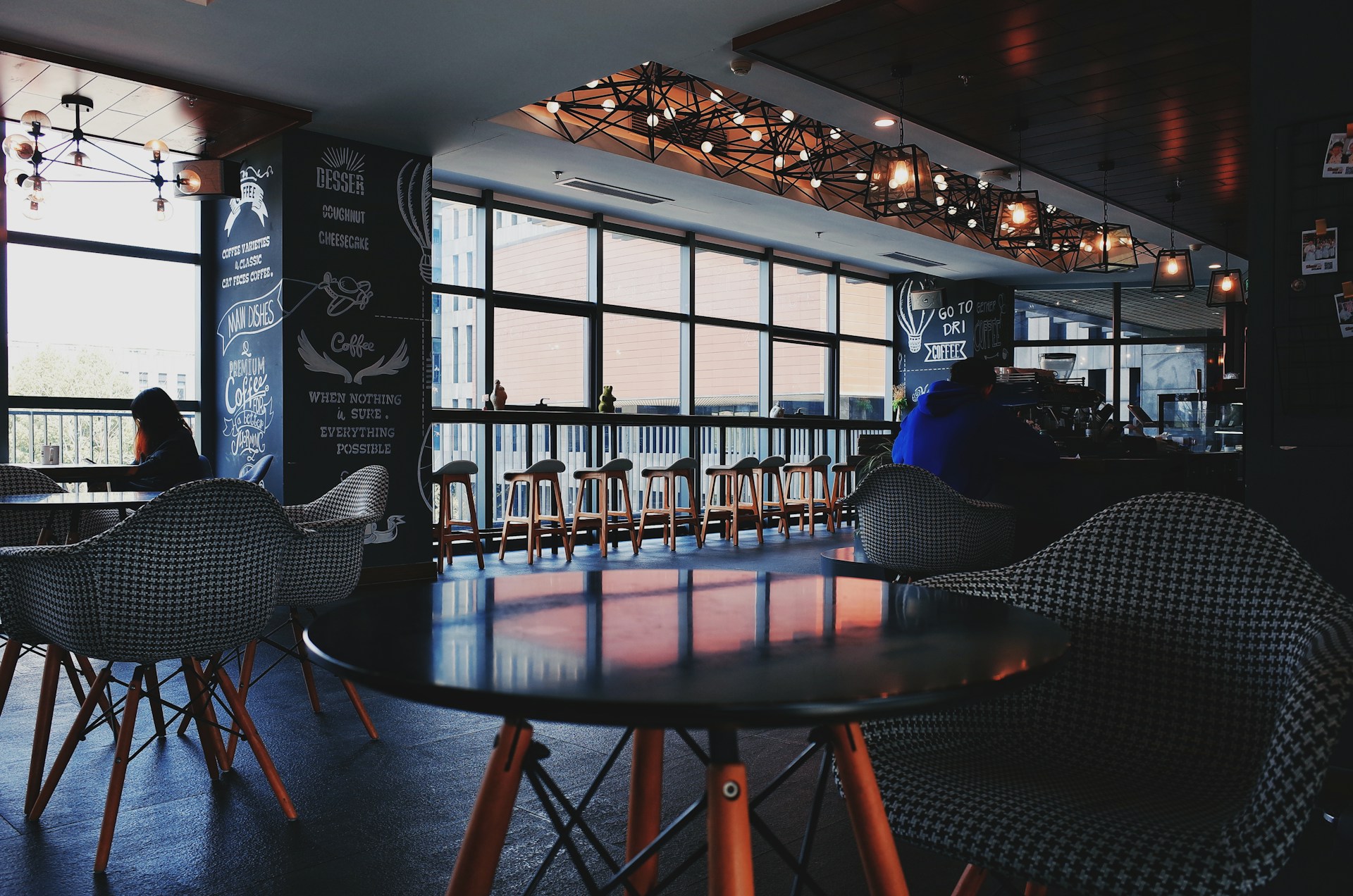 A cozy cafe interior featuring industrial decor, wooden tables, and patrons enjoying their meals.