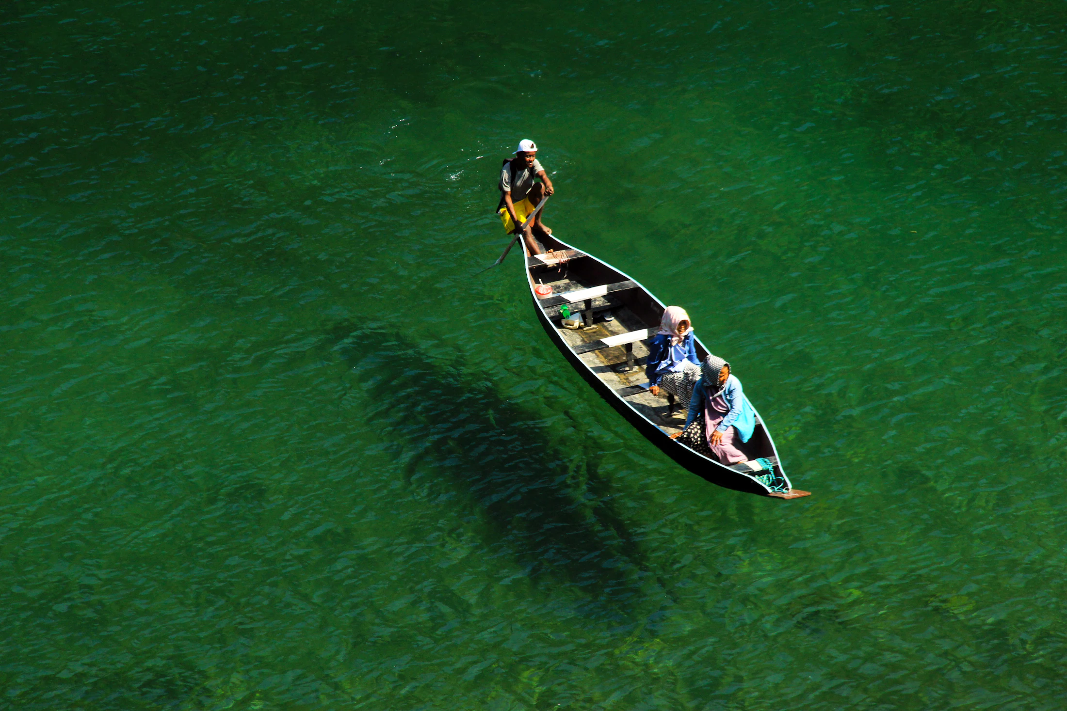 A wooden boat appearing to float over the glass-clear Umngot river at Dawki
